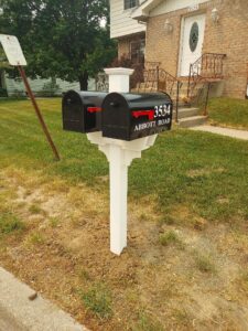 A couple of mailboxes on top of a white post.